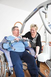 Heidi Genau hilft ihrem Mann per Lift in den ­Rollstuhl